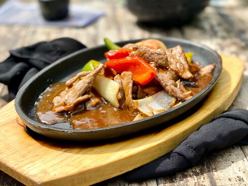 Sizzling beef on a hot plate with onions and capsicum.